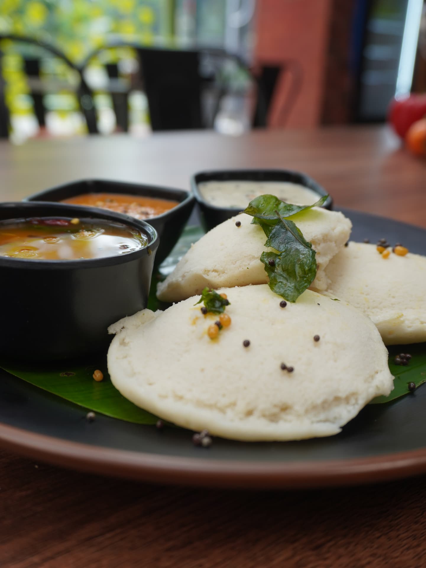 Soft idli on banana leaf with sambar and chutneys